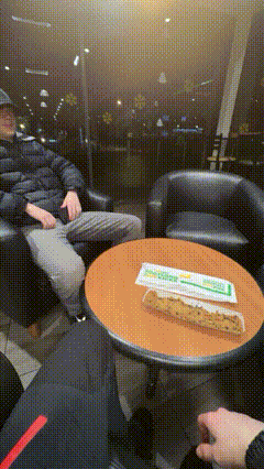 a man sits in a chair with a sandwich on a table