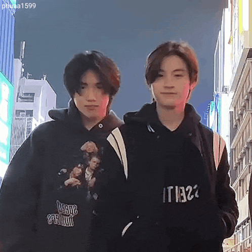 two young men are standing next to each other in front of a building .