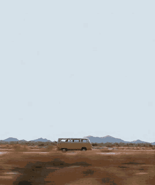 a yellow van is driving down a dirt road .