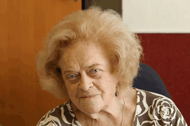 a woman with blonde hair and blue eyes is wearing a brown and white striped shirt