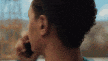 a man is talking on a cell phone in front of a window