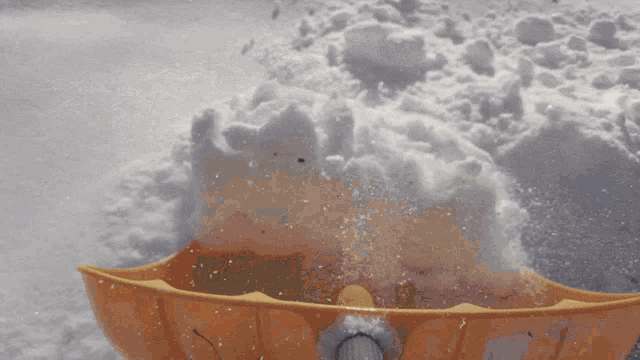 a yellow snow shovel is sitting in the snow near a pile of snow