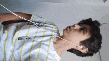 a person wearing a striped shirt and ear buds with the letter x on it