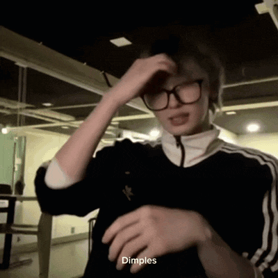 a young man wearing glasses and a black jacket is making a funny face and says dimples .