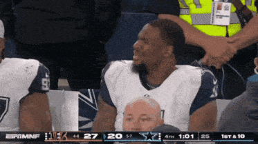 a man in a dallas cowboys jersey looks at the scoreboard