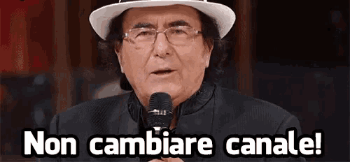 a man wearing a hat and glasses is holding a microphone and says non cambiare canale !