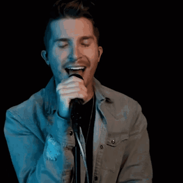 a man singing into a microphone with his mouth open