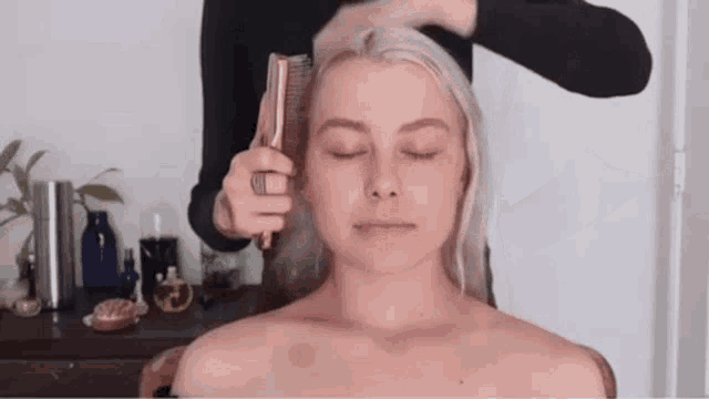 a woman without a shirt is getting her hair done by a hairdresser .