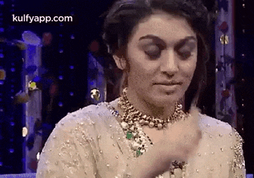 a woman wearing a necklace and a white dress is making a face .