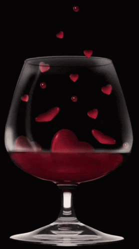 hearts are falling into a wine glass filled with red liquid