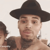 a shirtless man wearing a hat and a tattoo on his chest