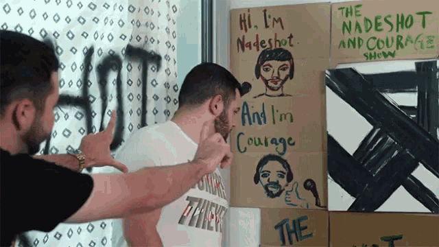 two men standing in front of a sign that says " hi i 'm nadeshot "