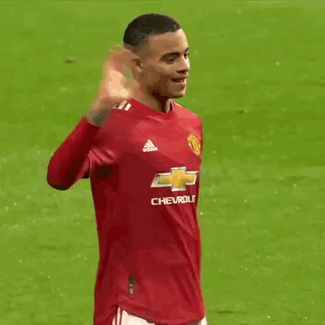 a soccer player wearing a red shirt with chevrolet on it is waving his hand .
