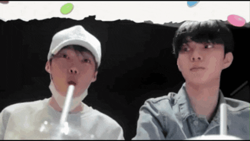 two young men are sitting next to each other drinking through straws