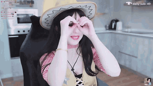 a woman wearing a cowboy hat making a heart with her hands
