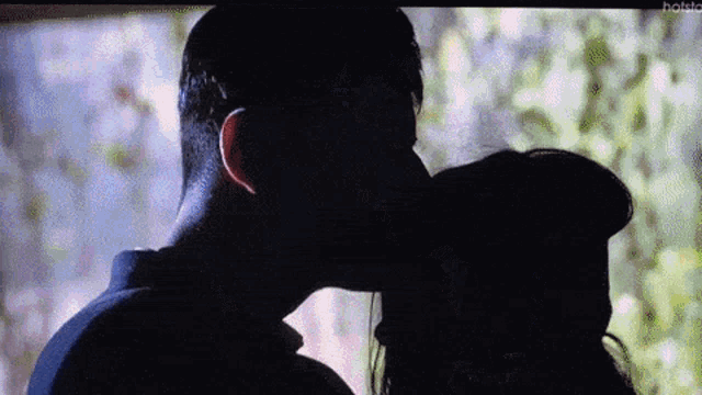 a man and a woman are kissing in the shadows on a television screen .