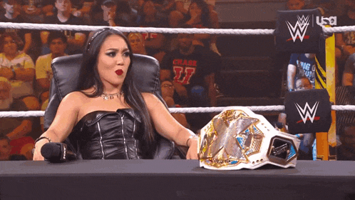 a woman sitting in a chair next to a wrestling belt that says x