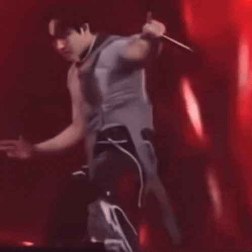 a man is holding a microphone in his hand while dancing on stage