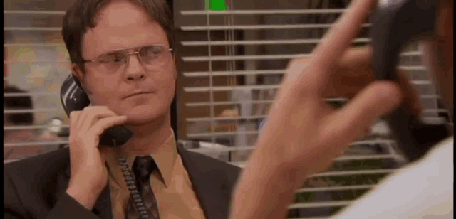 a man in a suit and tie is talking on a telephone .