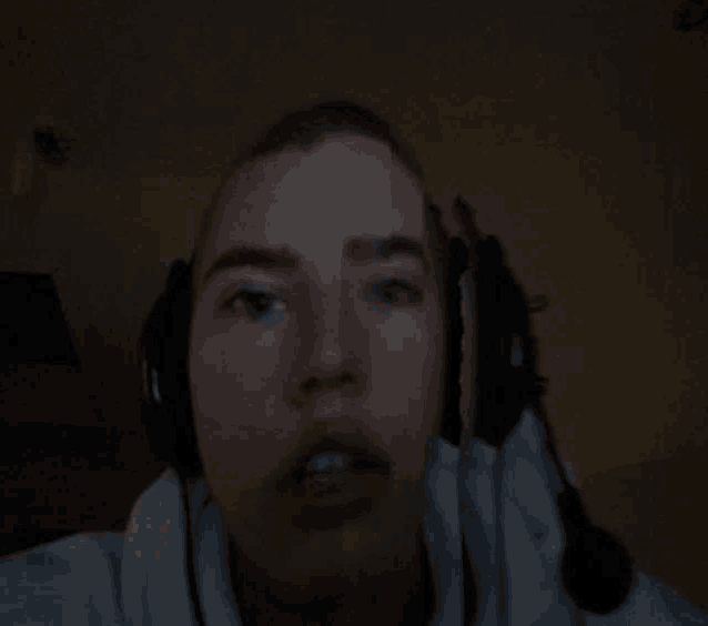 a man wearing headphones looks at the camera in the dark