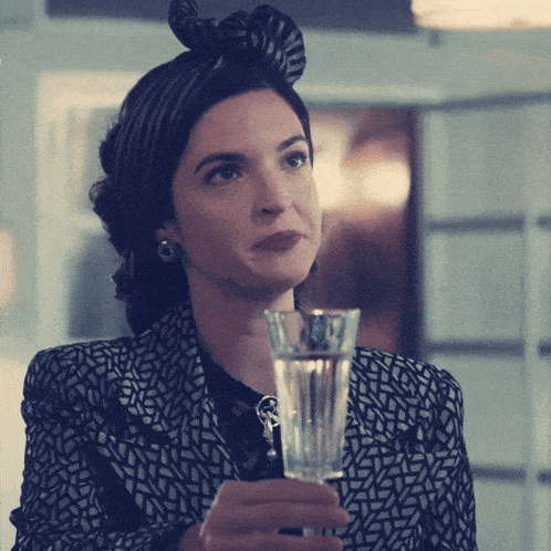 a woman holding a glass of water in her hand