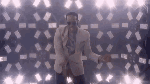 a man in a suit and tie is dancing on a stage in front of a wall of lights .
