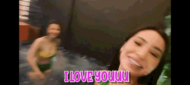 two women in bikinis are standing in a pool with the words i love youuu written on the bottom