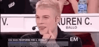 a man is sitting in a stadium with a microphone in his hand and making a funny face .