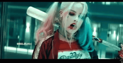 a woman in a harley quinn costume is holding a bat .