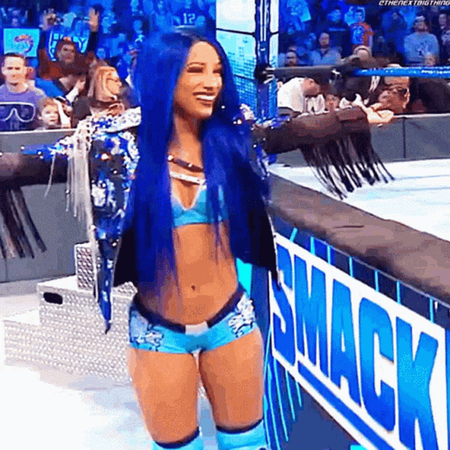 a woman with blue hair is standing in front of a smack sign .