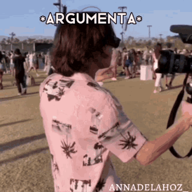 a man in a pink shirt is holding a camera and says " argumenta " on the screen