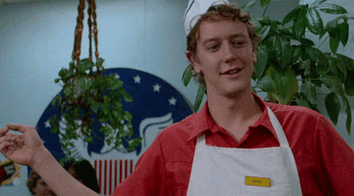a man wearing a red shirt and white apron has a name tag that says chris