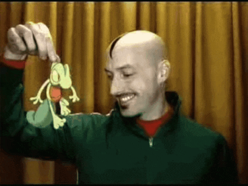 a man in a green jacket is holding up a cartoon frog .