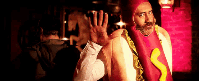 a man in a hot dog costume waves his hand