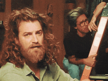 a man with curly hair and a beard is holding a ladder