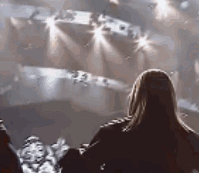 a woman is sitting in front of a stage with lights shining on it
