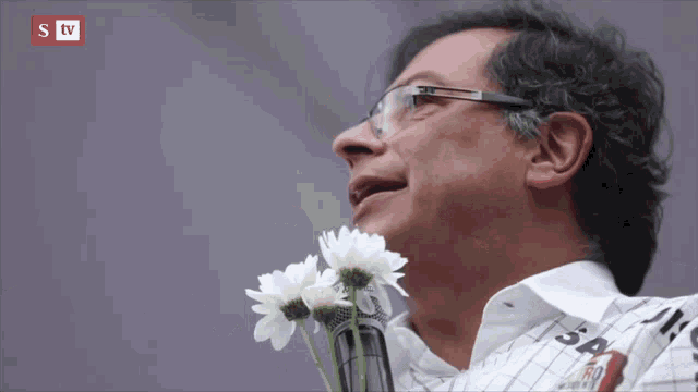 a man is holding flowers in front of a microphone with a stv logo in the background