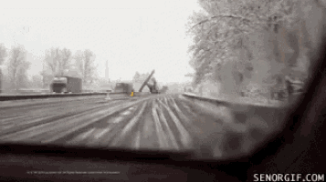 a car is driving down a snowy highway with a broken bridge in the background .