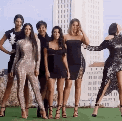 a group of women standing next to each other in front of a tall building .