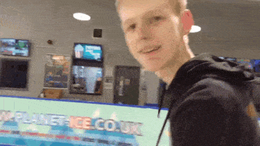 a young man stands in front of a planet-ice.co.uk sign