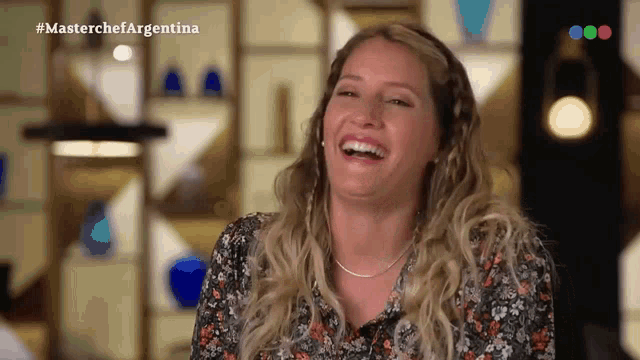 a woman is laughing in front of a sign that says masterchef argentina on it