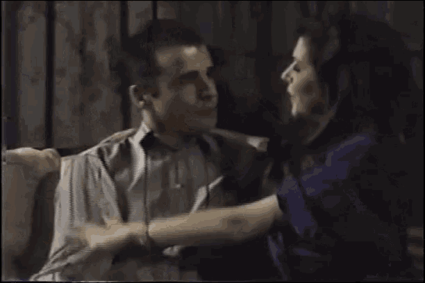 a man and woman are hugging each other while sitting on a couch .