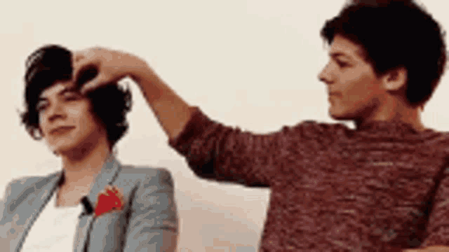a man is touching another man 's hair while another man looks on .