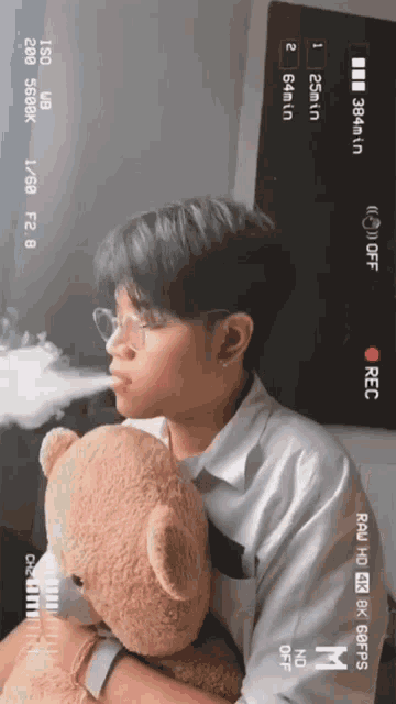 a young man is holding a teddy bear while smoking