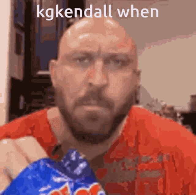 a bald man with a beard is holding a bag of potato chips and says kgkendall when