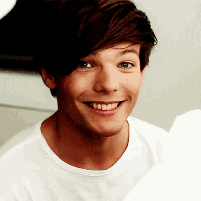 a young man in a white shirt is smiling