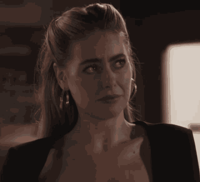 a woman wearing hoop earrings and a black top looks at the camera