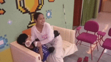 a woman is sitting on a couch holding a child 's hand with a trophy on the wall behind them .