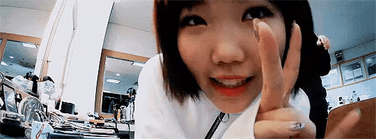 a woman is smiling and giving a thumbs up sign while looking at the camera .