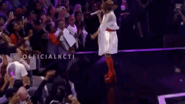 a woman singing in front of a crowd with the words officialrcti visible